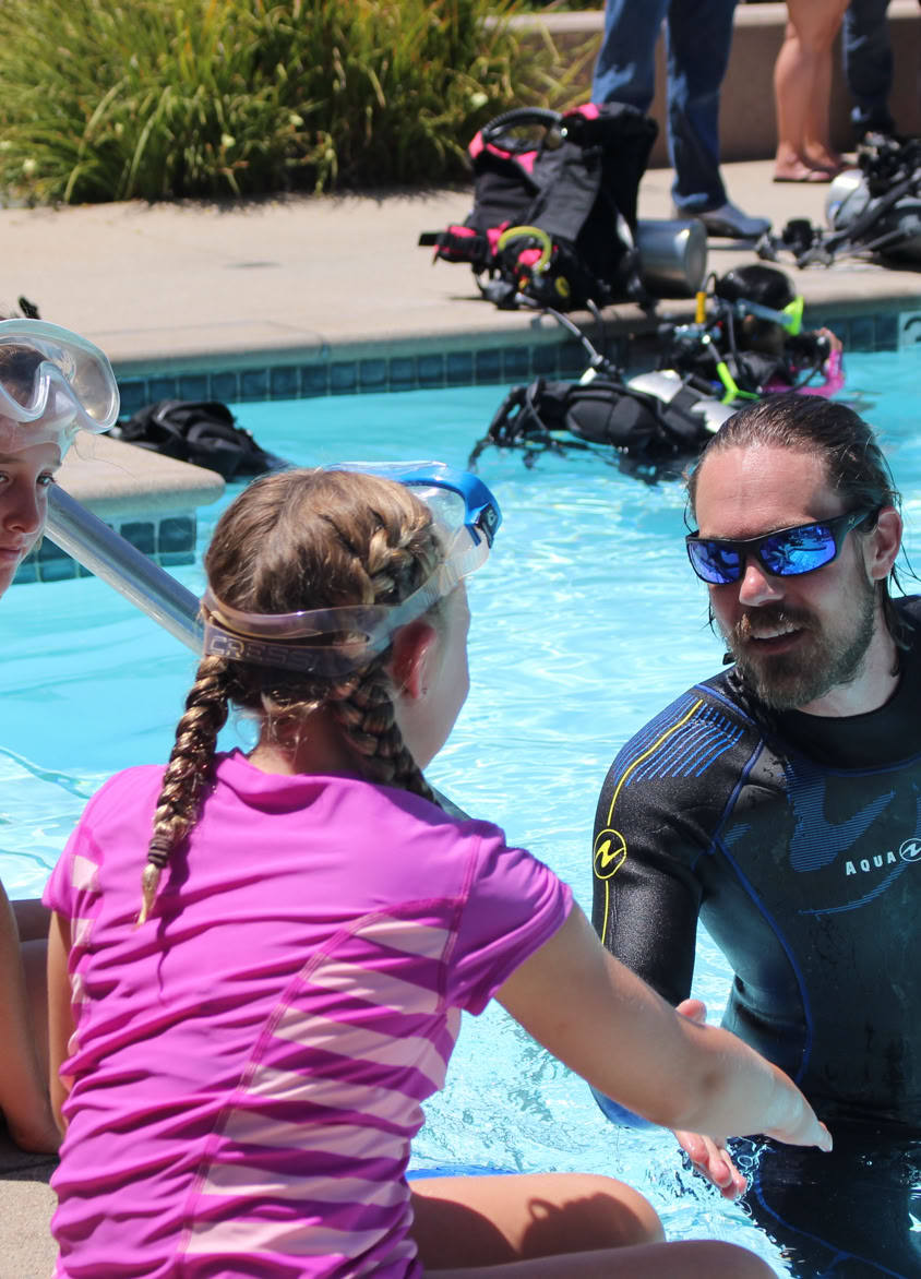 A young advanture enjoying scuba diving in a swimming pool.